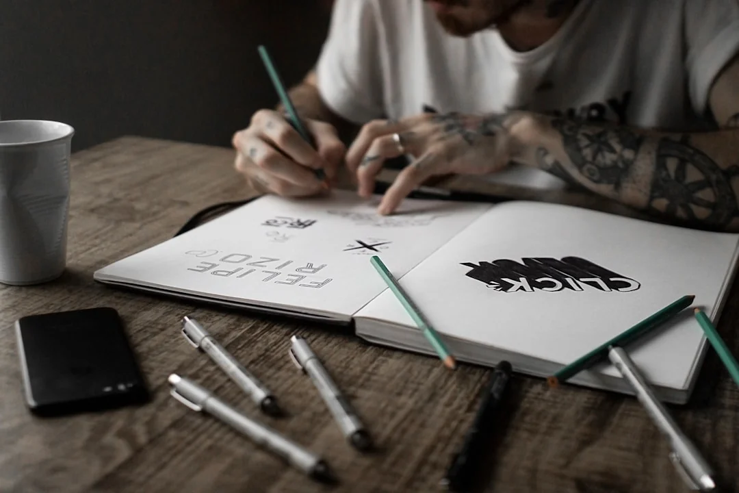Une vue plongeante d’un espace de travail minimaliste avec un ordinateur portable et une feuille blanche posés sur une table en bois.